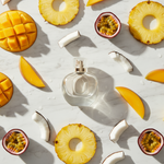 Una boccetta di profumo trasparente al centro, circondata da fette di mango, ananas, cocco e frutto della passione in modo totalmente sparso su un tavolo in marmo. Atmosfera solare ed esotica, luce calda dorata, riflessi morbidi e texture succose. Stile fotografico raffinato, mood luminoso e gioioso, sensazione di freschezza tropicale. Vista top view dall'alto